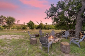 An outdoor seating area with chairs and a fire pit surrounded by trees.