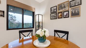 A dining table with a vase of white flowers, black chairs, and framed pictures on the wall.