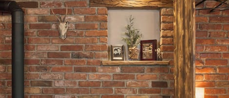 A cozy room with a brick wall, a fireplace, a sofa, and a small shelf with decorative items.