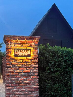 A brick wall with a neon sign reading 'PODROOM' and 'LouMarYvo'.
