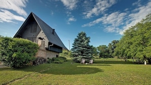 A building with a sloped roof, surrounded by a well-maintained lawn and trees. - Cozy little house near Zagreb and airport. Private garden around house. (Dugo Selo)