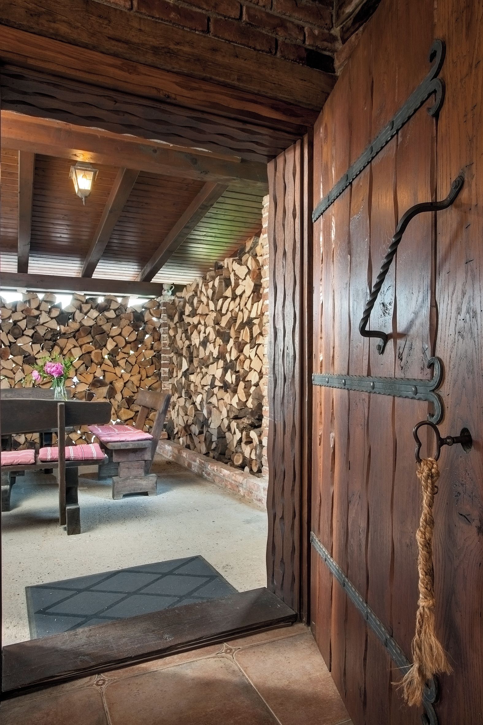 Un interior rústic amb una porta de fusta, una paret de pedra i un banc amb coixins.
