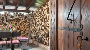 Un interior rústic amb una porta de fusta, una paret de pedra i un banc amb coixins.