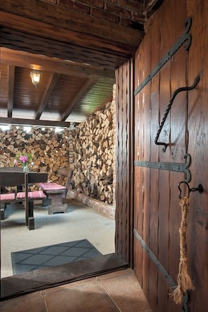 A rustic interior with a wooden door, a stone wall, and a bench with cushions.
