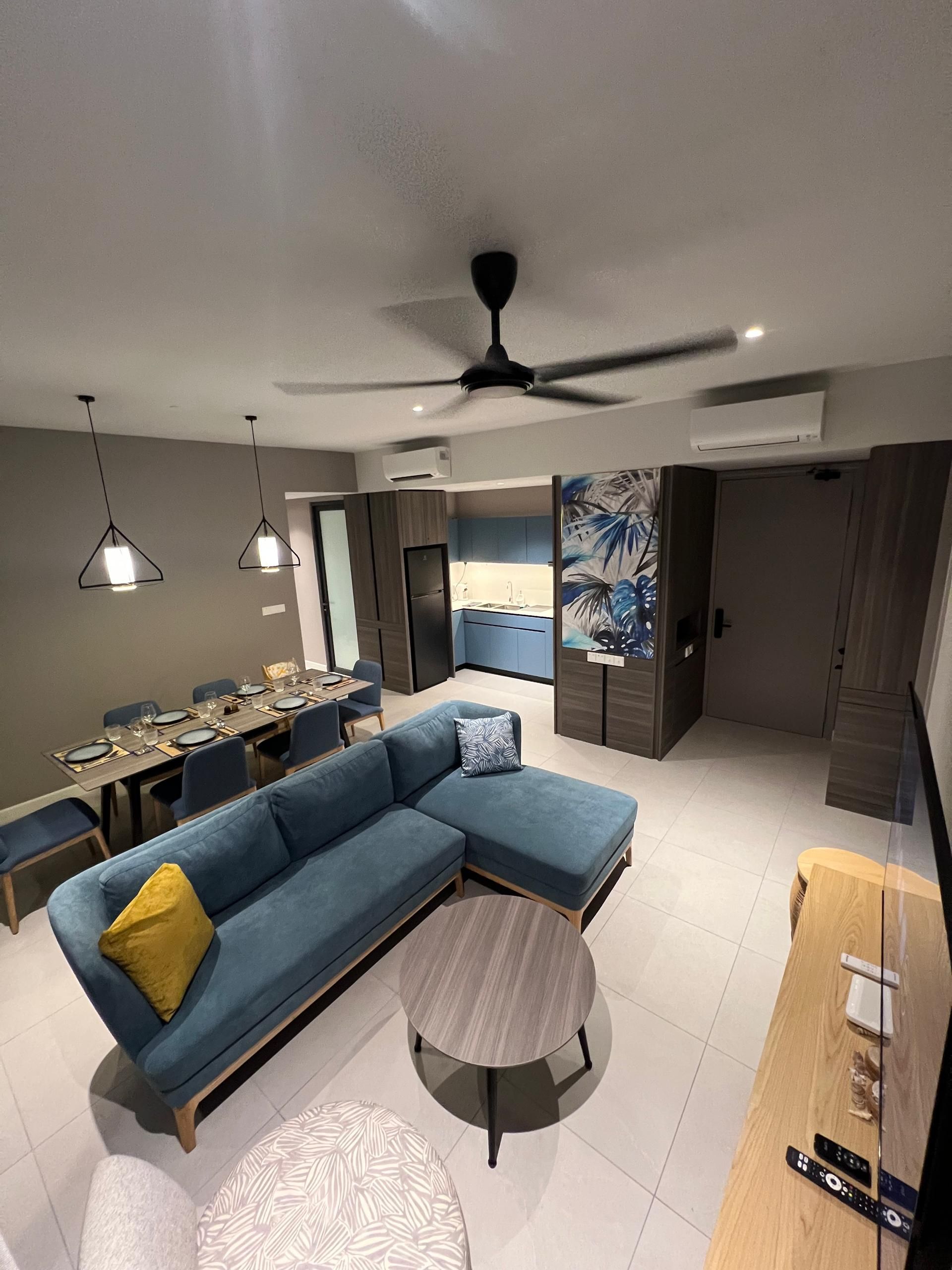 A modern living room with a sectional sofa, a dining table set for six, a ceiling fan, and an air conditioning unit.