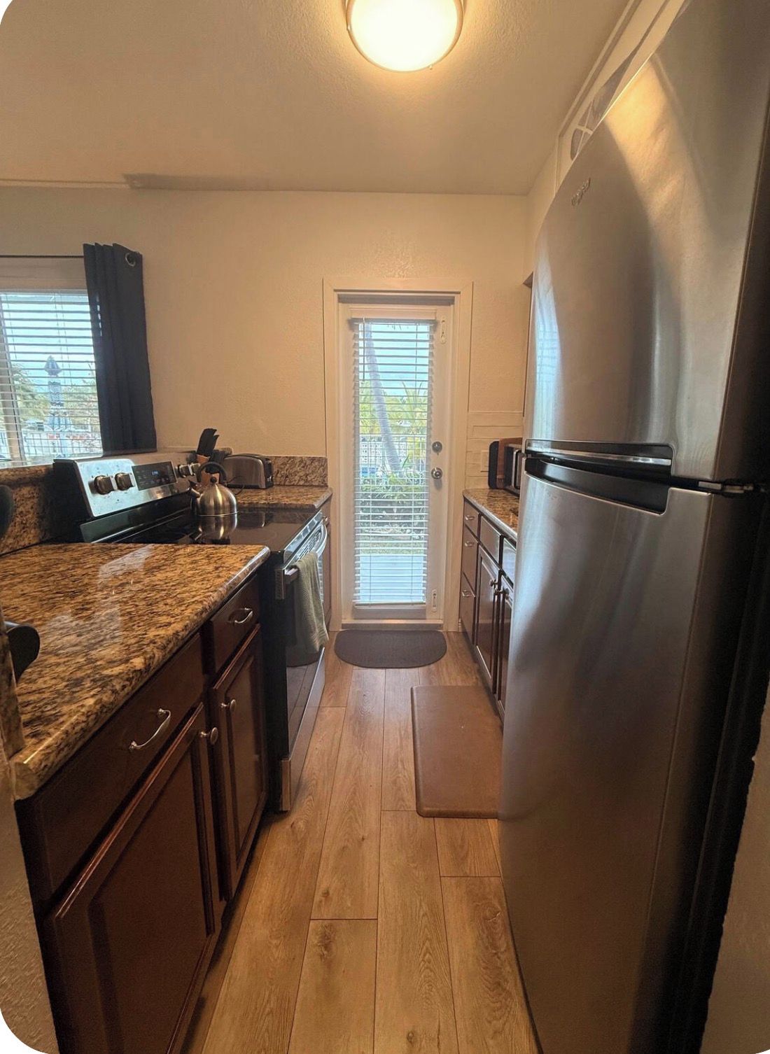 A compact kitchen with a stainless steel refrigerator, a gas stove, and wooden cabinets.