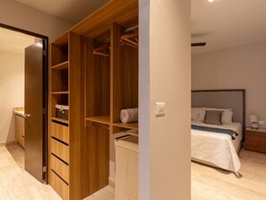 A bedroom with a bed, a bedside table, a nightstand, a wardrobe, and a door leading to another room. - Kanaa Marina - Luxury Oceanview Residence (Progreso)