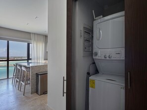 A modern kitchen with a bar area, a view of the ocean, and a washing machine. - Kanaa Marina - Luxury Oceanview Residence (Progreso)