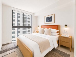A hotel room with a large window, a bed with white bedding, a wooden headboard, a nightstand with a lamp, and a framed picture on the wall. - Modern Downtown Miami Retreat with Private Balcony (Miami)