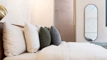 A modern bedroom with a wooden bed frame, a bedside table, and a wall-mounted mirror.