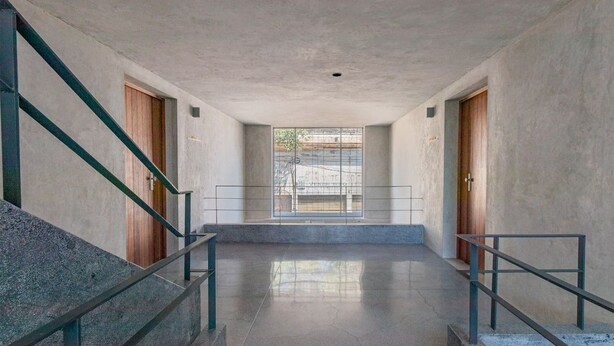 Un intérieur moderne avec un sol en béton, des rampes en métal et des portes en bois.