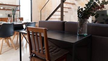 A modern dining area with a wooden chair, a glass vase with a plant, and a sofa.