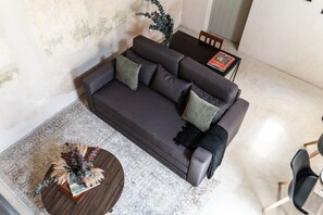 A modern living room with a dark sofa, a round coffee table, and a patterned rug.