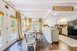 A dining area with a table and chairs, a kitchen with white cabinets, and a sign labeled 'GROCERIES'. - Heavenly Honey Bear | Helen Getaway w/ Fire Pit (Helen)