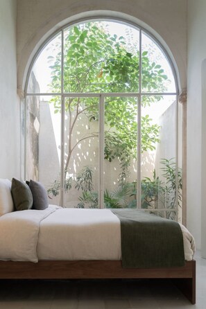 Cama com vista para uma árvore pela janela.