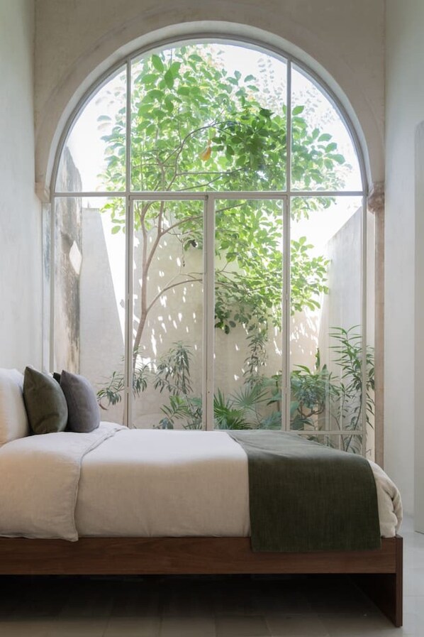 Ein Bett mit Blick auf einen Baum durch ein Fenster.