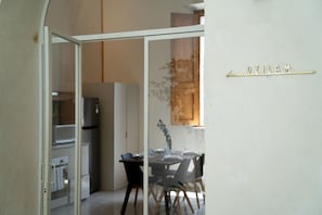 Quarto com porta de vidro que dá para uma área de refeições, geladeira e armário.