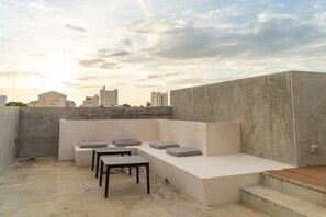 A rooftop terrace with a seating area, a table, and a view of the city skyline. - Izamal · 2 rec · 2 baños · Tina en rooftop (Mérida)
