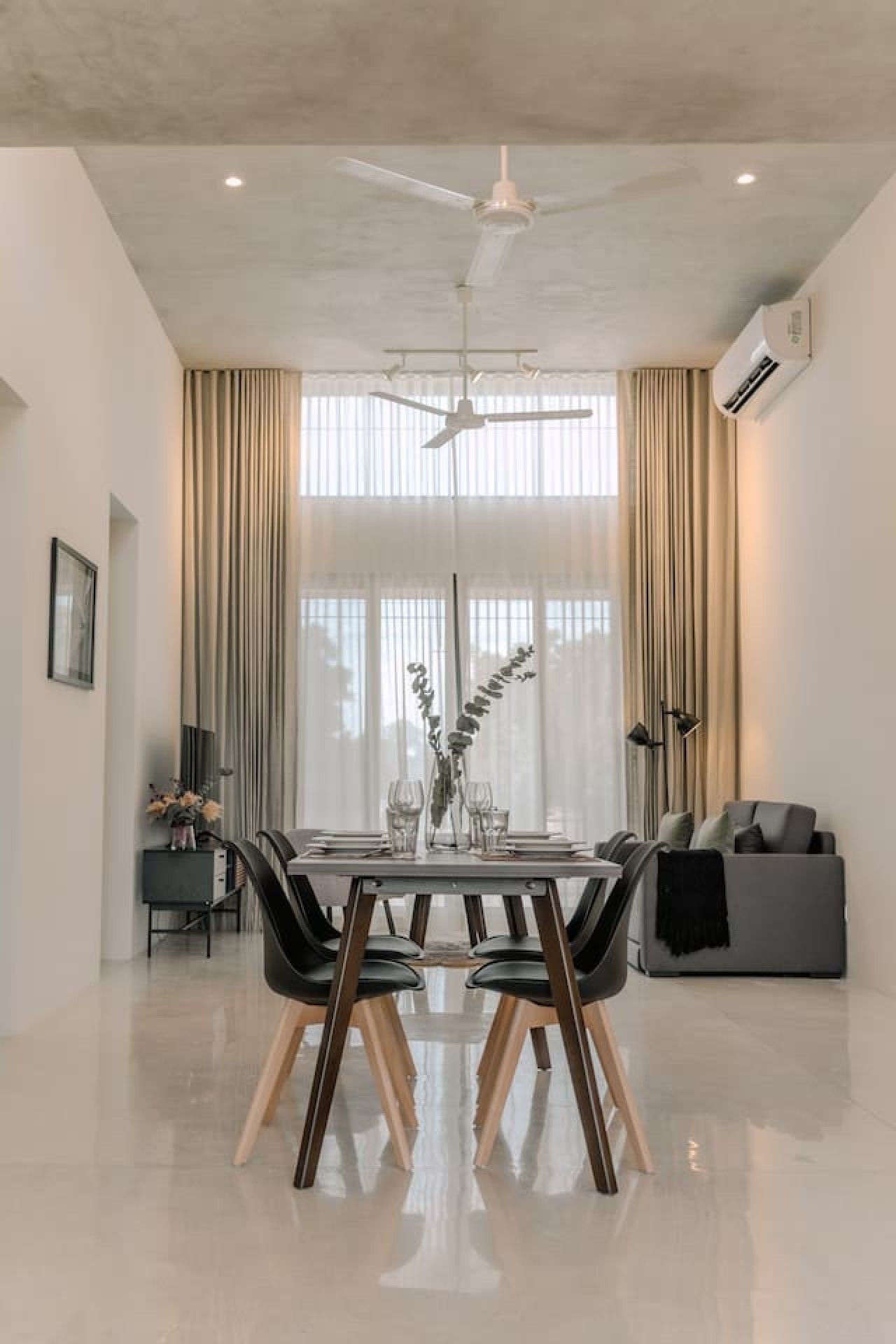A modern dining area with a table set for four, a ceiling fan, and an air conditioning unit.