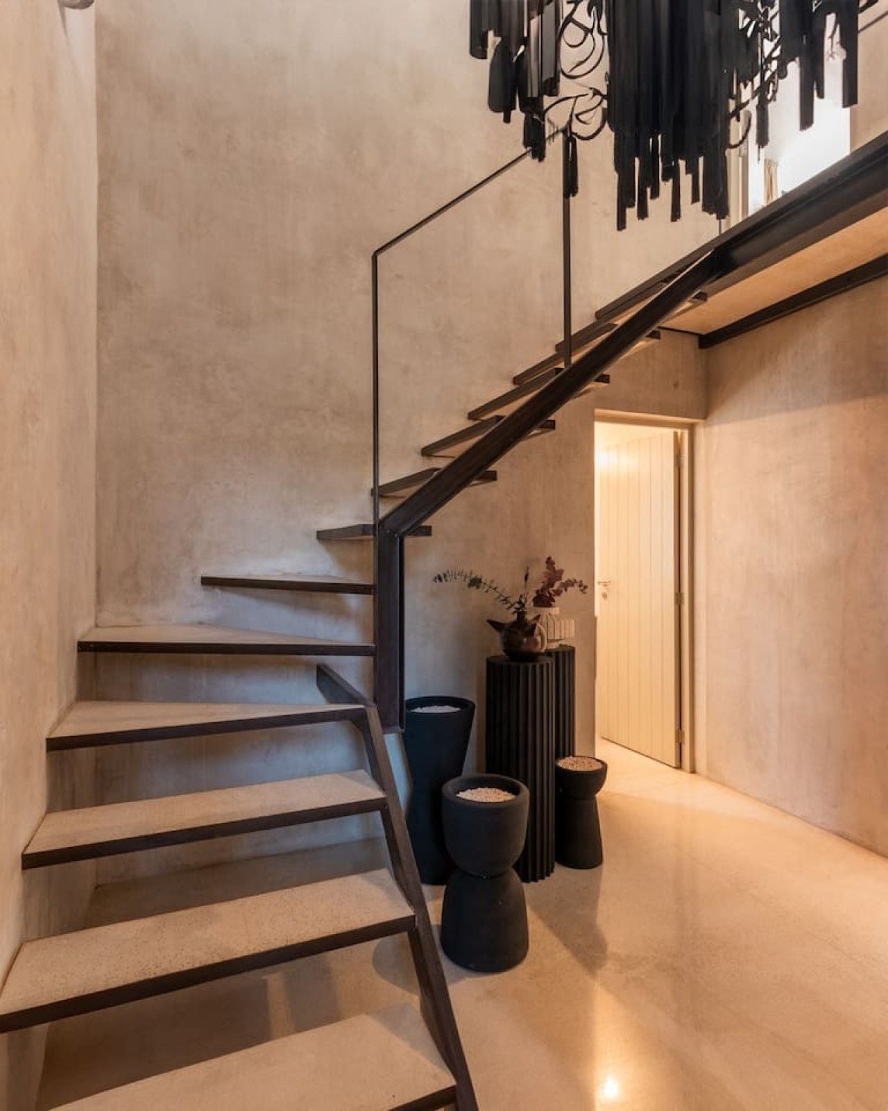 A modern interior with a staircase, a black metal railing, and a minimalist design.
