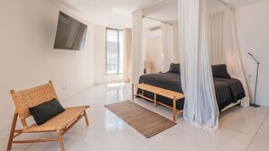 Quarto moderno com cama de dossel, uma cama de solteiro, uma cadeira e uma mesa de cabeceira.