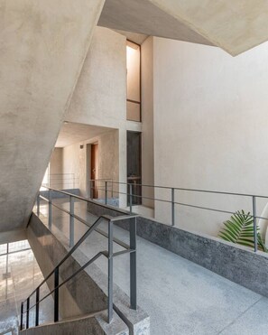 A modern interior with a staircase, concrete walls, and a glass railing. - Ekbalam · 1 rec · 1 baño · Chic con alberca (Mérida)