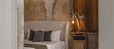 A bedroom with a bed, a nightstand, a lamp, and a wooden wardrobe.