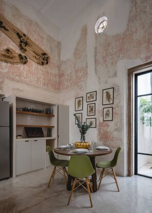 A dining area with a round table, green chairs, and a natural light source. - Acanceh · 1 rec · 1 baño · Plunge pool y rooftop (Mérida)