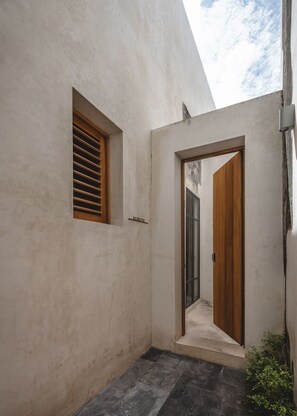 A narrow hallway with a wooden door and a window with horizontal blinds. - Acanceh · 1 rec · 1 baño · Plunge pool y rooftop (Mérida)