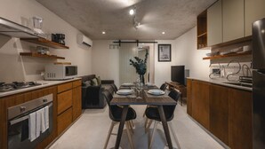 A modern kitchen with a dining area, wooden cabinets, a built-in oven, and a flat-screen TV. - Maní · 1 rec · 1 baño · Terraza y alberca (Merida)