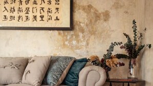 A living room with a sofa, a coffee table, a side table with a vase of flowers, and a wall with a framed piece of calligraphy. - Maní · 1 rec · 1 baño · Terraza y alberca (Merida)