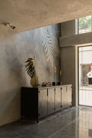 Een modern interieur met een betonnen muur, een potplant en een glazen deur die naar buiten leidt.