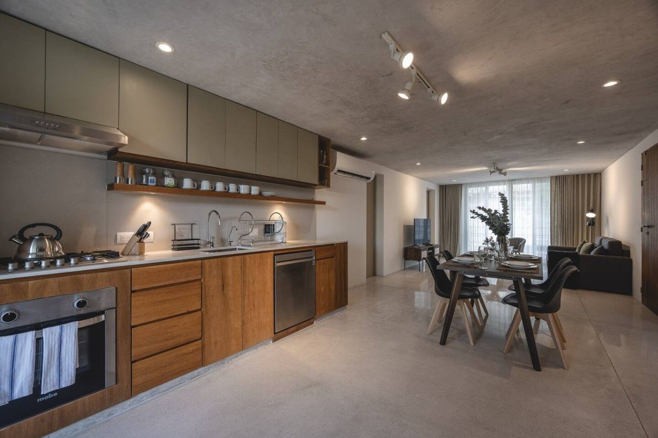 Een moderne keuken met een inbouwoven, vaatwasser en een eethoek met een tafel en stoelen.