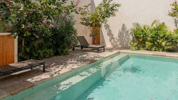 A swimming pool with two sun loungers and a wooden cabinet.