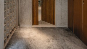 Um corredor com teto de concreto, porta de madeira e guarda-roupa de madeira.