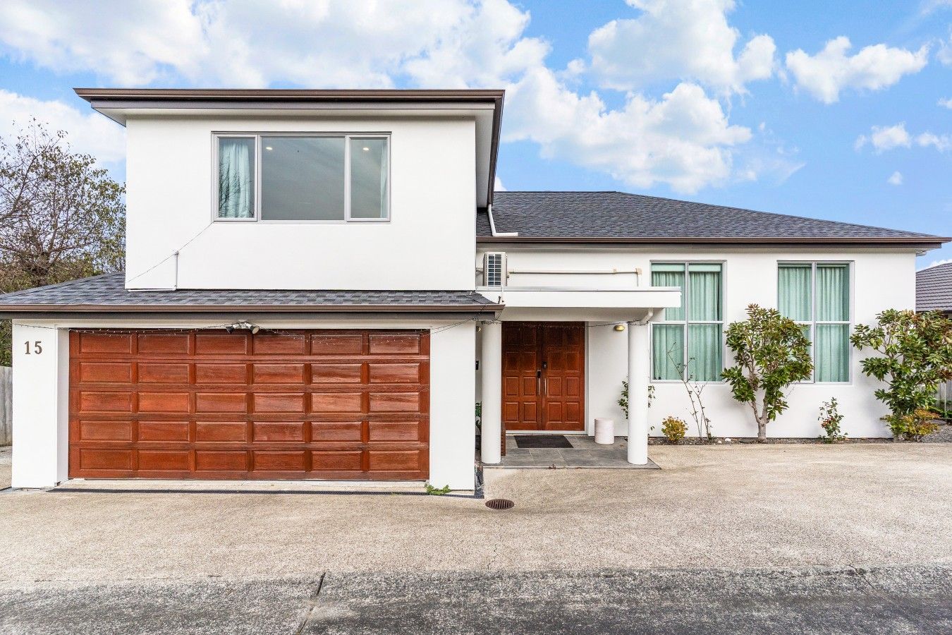 A two-story residential building with a garage, a front door, and a small porch.