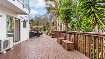 Eine Holzterrasse mit Gartenmöbeln, einem Poolbereich und Blick auf die umliegende Natur.