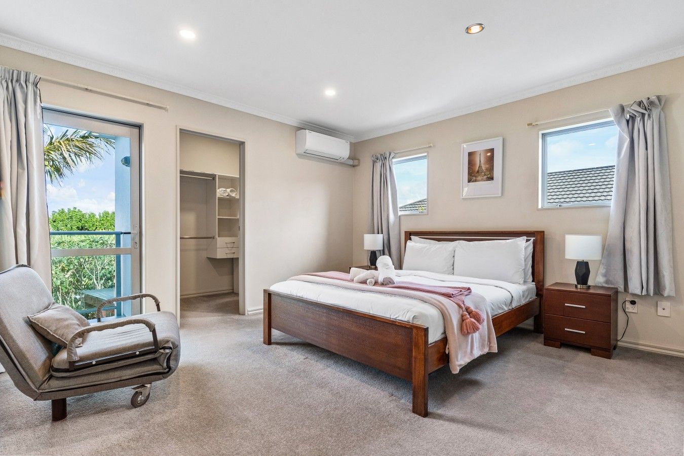 A bedroom with a bed, bedside tables, a chair, a closet, and a window with curtains.