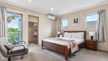 A bedroom with a bed, bedside tables, a chair, a closet, and a window with curtains.