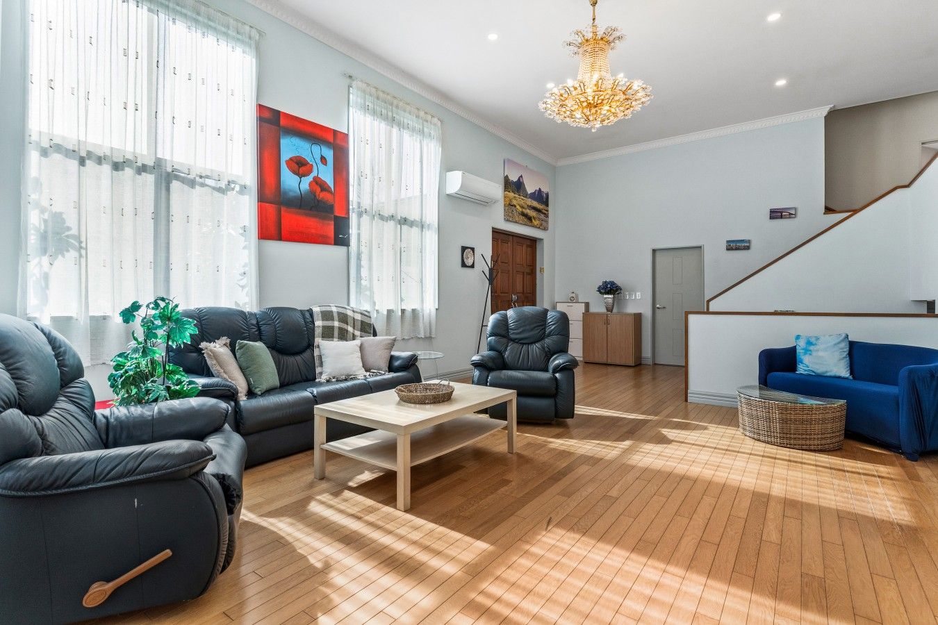 A modern living room with a sofa, armchairs, a coffee table, and a blue couch.