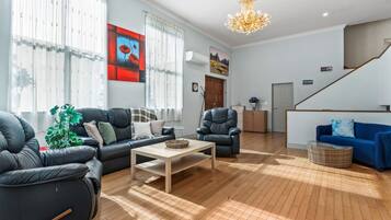 A modern living room with a sofa, armchairs, a coffee table, and a blue couch.