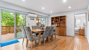 Un comedor moderno con mesa de madera y sillas estampadas, unidad de aire acondicionado empotrada y un mueble de madera con estantes.