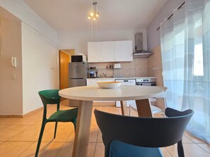 A modern kitchen with white cabinets, a round dining table, and chairs. - Quiet 1BR + Pool, 300m to beach, 100m to Supermarket, Walk to Dining (Limassol)
