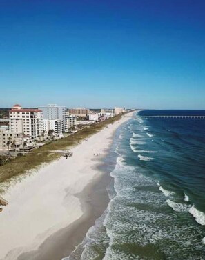 A coastal hotel with a beach view, a pier extending into the water, and a clear sky. - Cozy 2 BR Apt |King Bed |Pool |Gym| Close to Mayo. (Jacksonville)