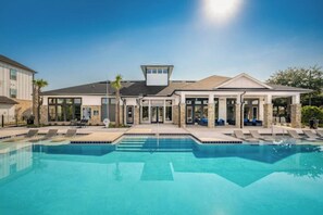 Ein modernes Gebäude mit Swimmingpool, Liegestühlen und einer überdachten Terrasse.