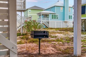 A beach house with a covered porch, a grill, and a staircase leading to the upper level. - Bikini Bottom · New Listing! Steps to Beach, Gulf-View Porches & Pool (Gulf Shores)
