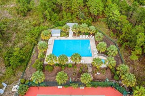 An aerial view of a property with a swimming pool surrounded by palm trees and a red-roofed tennis court. - Bikini Bottom · New Listing! Steps to Beach, Gulf-View Porches & Pool (Gulf Shores)