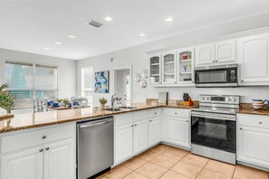 A modern kitchen with white cabinetry, a built-in microwave, and a stainless steel dishwasher. - Bikini Bottom · New Listing! Steps to Beach, Gulf-View Porches & Pool (Gulf Shores)