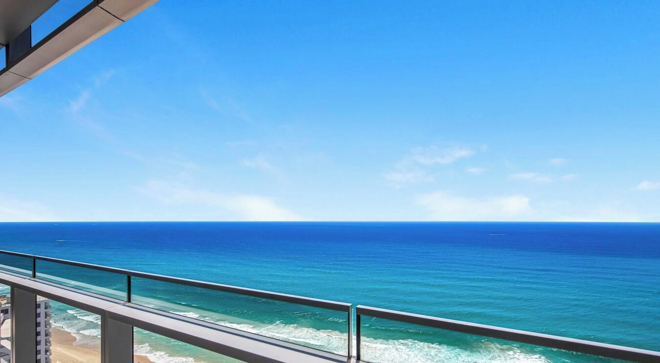Een balkon met uitzicht op de oceaan en een heldere lucht.