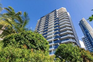A high-rise hotel with multiple balconies, surrounded by lush greenery. - Beachfront Surfers Paradise Apartment - Stunning Ocean Views (Surfers Paradise)